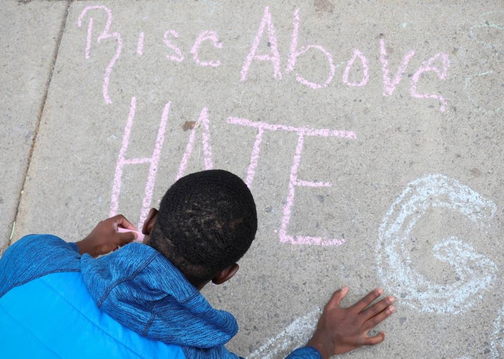 A boy writes a message on the sidewalk near a memorial in the wake of a weekend shooting at a Tops supermarket in Buffalo, New York May 18, 2022.  ― Reuters pic