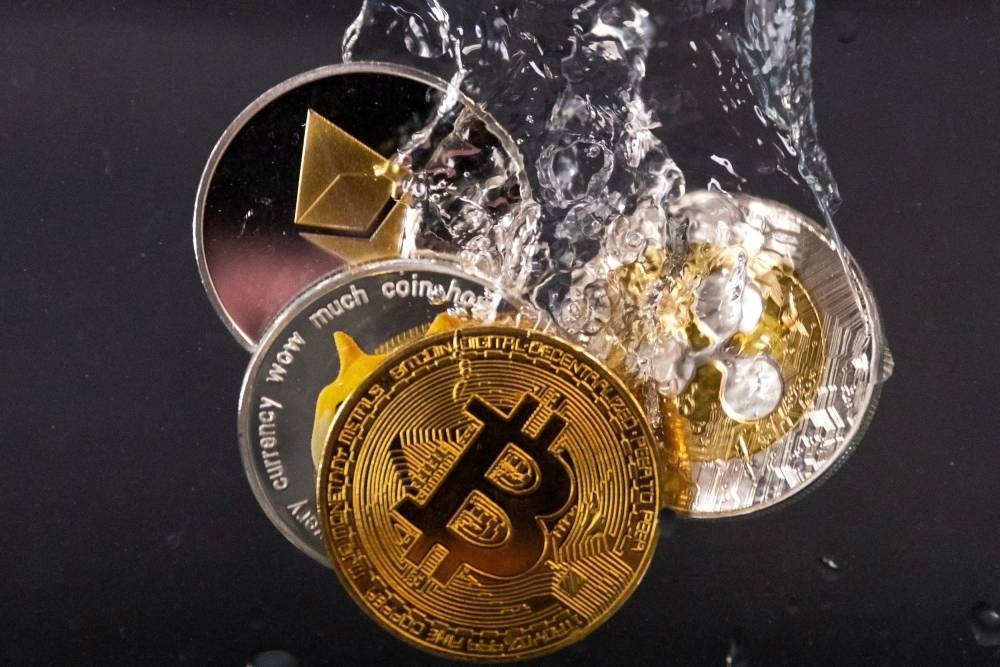 Souvenir tokens representing cryptocurrency networks Bitcoin, Ethereum, Dogecoin and Ripple plunge into water in this illustration taken May 17, 2022. — Reuters pic