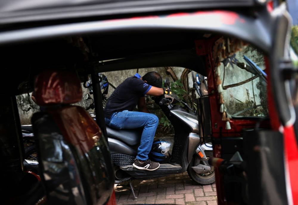 A man sleeps on his motorbike as he waits in a line to buy petrol near a fuel station, amid the country's economic crisis, in Colombo, Sri Lanka May 23, 2022. — Reuters pic