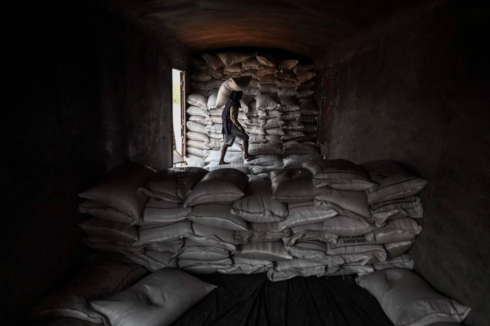 A worker loads a sack of wheat on a freight train at Chawa Pail railway station in Khanna, Punjab state May 19, 2022. — AFP pic 