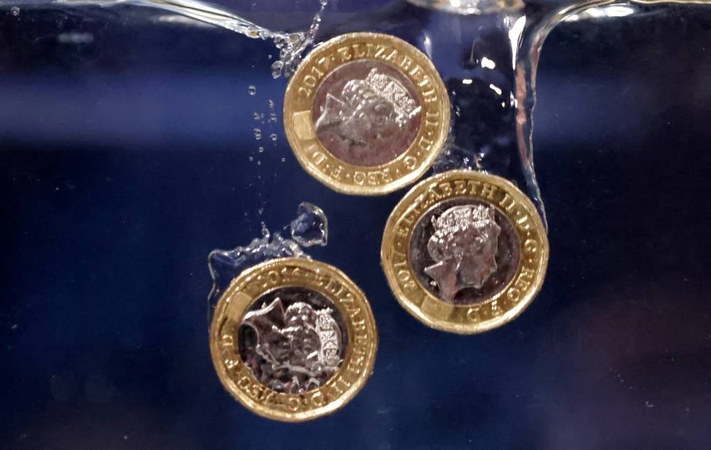 Pound coins plunge into water in this illustration taken, May 23, 2022. — Reuters pic