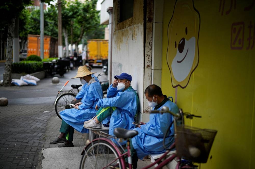 Workers in protective suits rest on a street during lockdown, amid the Covid-19 outbreak, in Shanghai, China May 28, 2022. ― Reuters pic