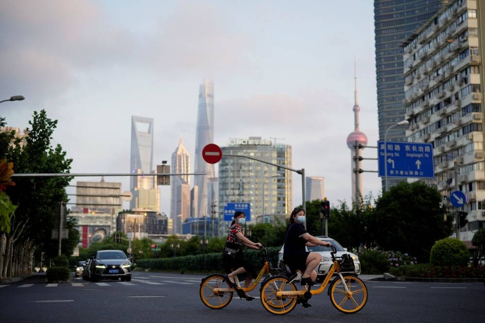 Women wearing face masks ride shared bicycles at an intersection, after the lockdown placed to curb the Covid-19 outbreak was lifted in Shanghai, China June 2, 2022. — Reuters pic