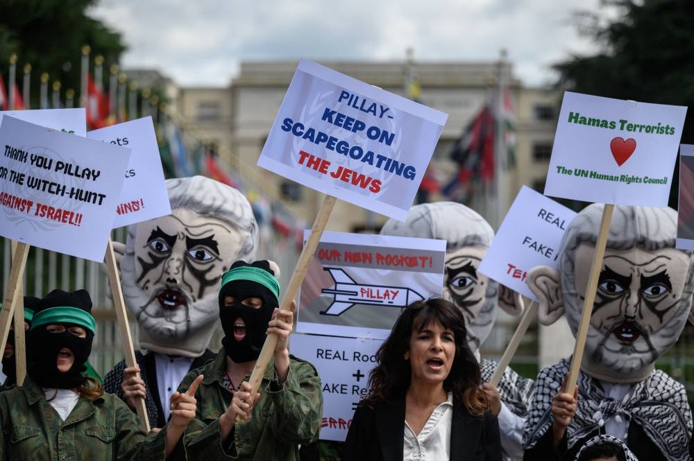 Israel's Defense Force reservists, wearing mask depicting Yahya Sinwar the Hamas chief in the Gaza Strip and holding Palestinian flags, protest outside the United Nations Offices in Geneva on June 7, 2022. — AFP pic