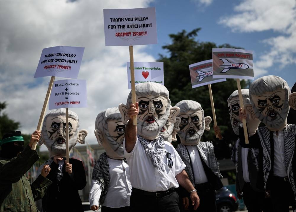 Israel's Defense Force reservists, wearing mask depicting Yahya Sinwar the Hamas chief in the Gaza Strip and holding Palestinian flags, protest outside the United Nations Offices in Geneva on June 7, 2022. — AFP pic