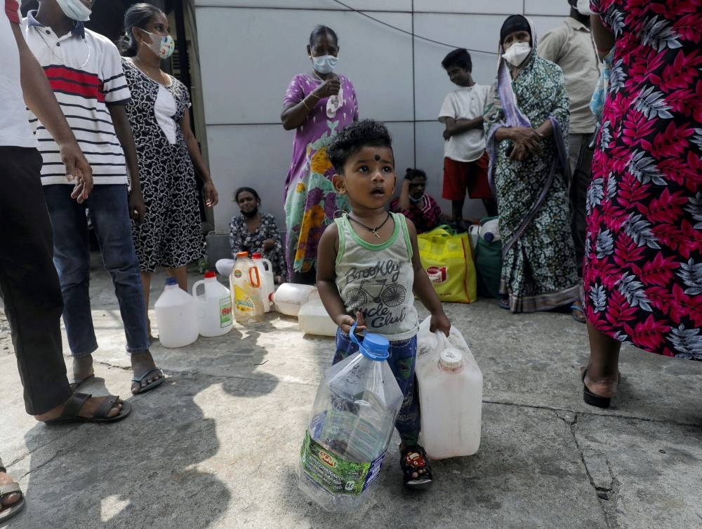 A child waiting to buy kerosene with his mother in the morning plays with cans, during a shortage of domestic gas as a result of country's economic crisis, at a fuel station in Colombo, Sri Lanka March 18, 2022. — Reuters pic