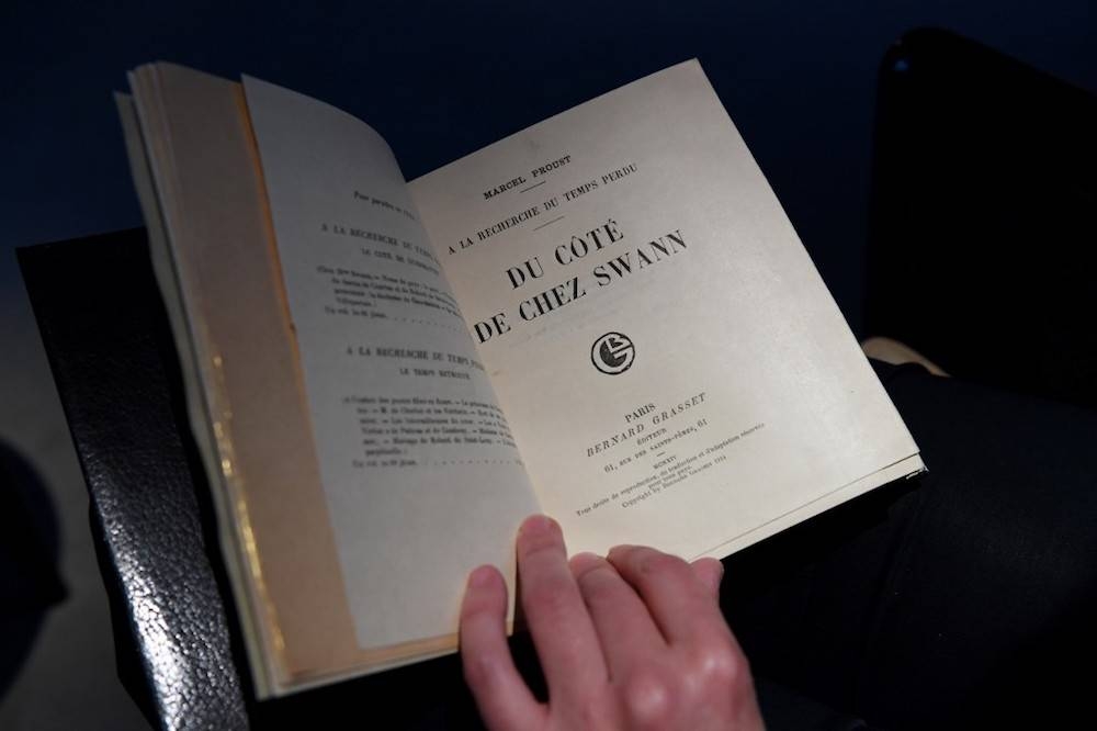 A woman holds a copy of French writer Marcel Proust  in Paris October 30, 2017 — AFP pic