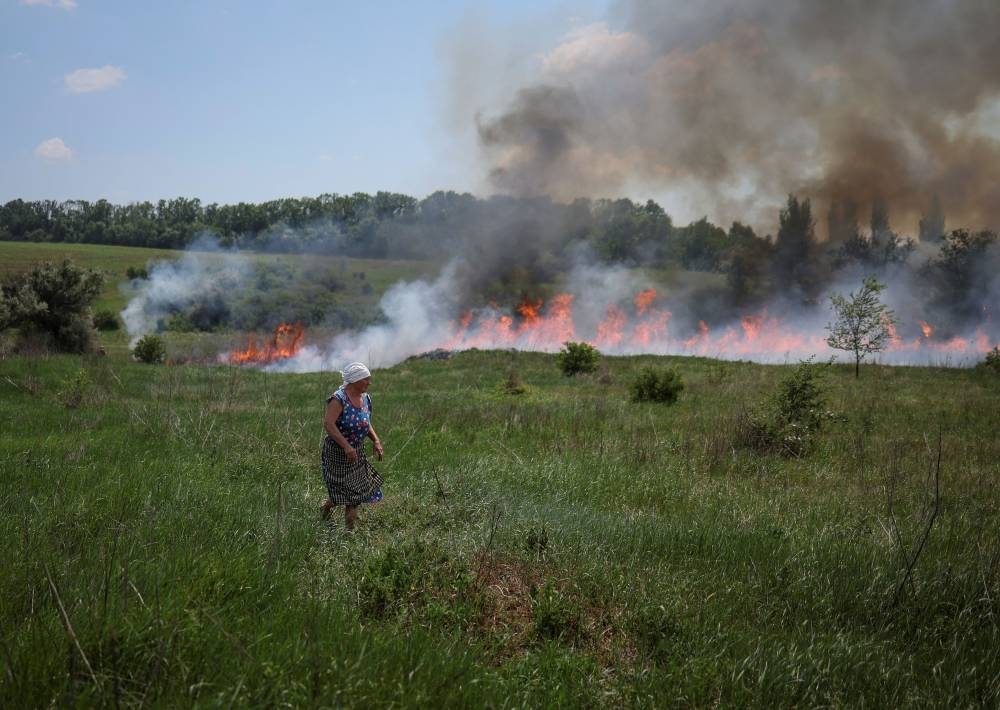 A local resident looks at grass that is on fire after a shelling, amid Russia's attack on Ukraine, near the town of Bakhmut, Donetsk region Ukraine June 12, 2022. — Reuters pic