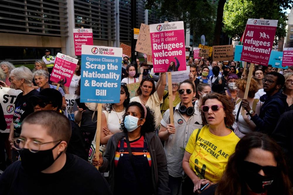 Protesters holds placards as they gather outside the Home Office in central London on June 13, 2022, to demonstrate against the UK government's intention to deport asylum-seekers to Rwanda. — AFP pic