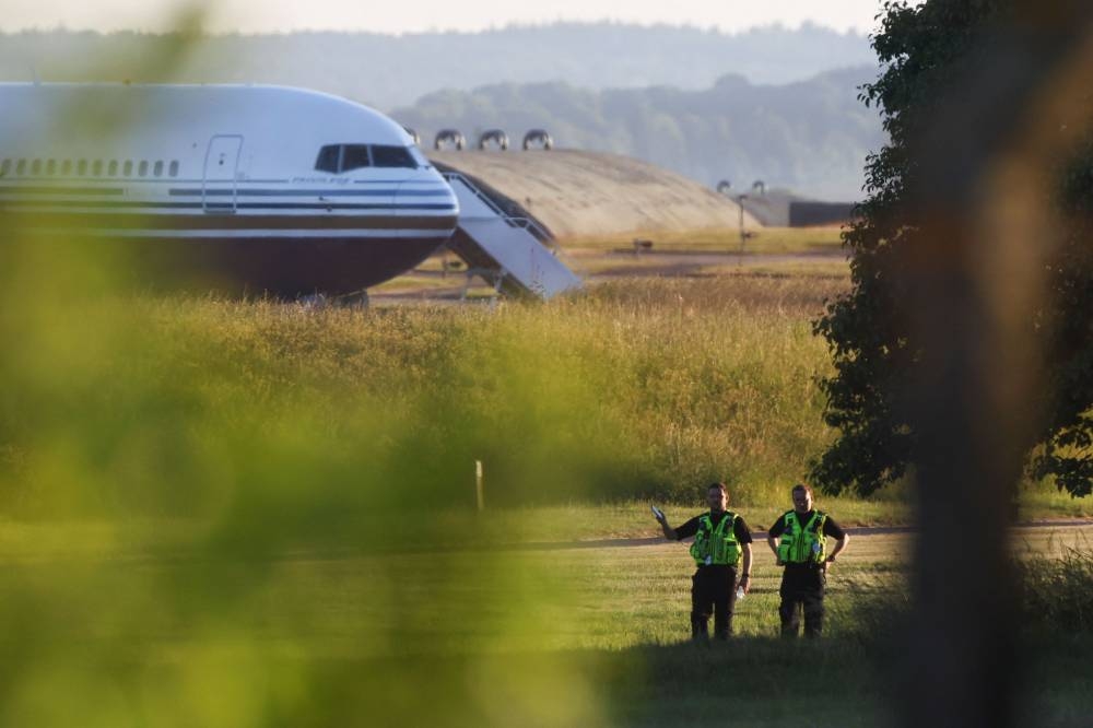 Police officers stand near a plane reported by British media to be first to transport migrants to Rwanda at MOD Boscombe Down base in Wiltshire, Britain June 14, 2022.  — Reuters pic