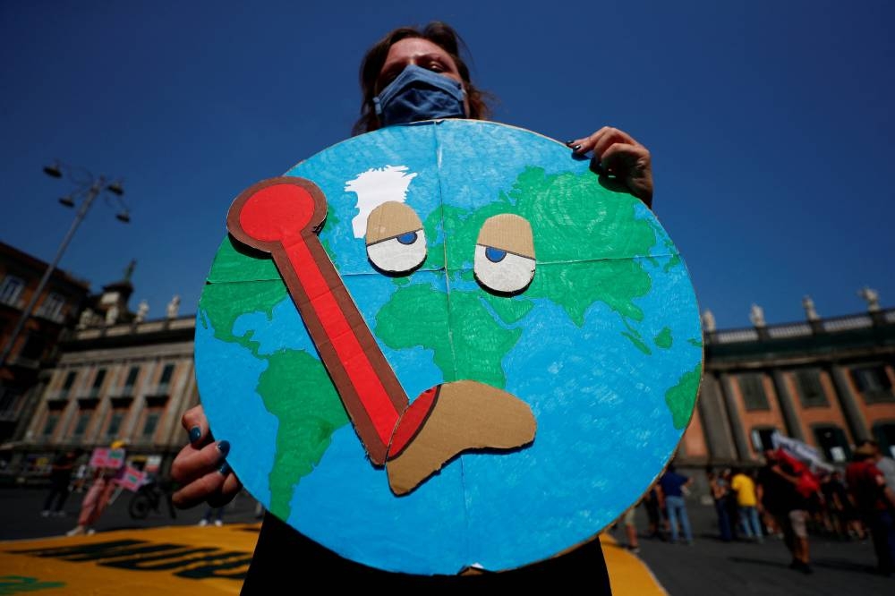 A person holds a placard as climate activists including Extinction Rebellion and Fridays for Future stage a protest demanding more action whilst G20 climate and environment ministers hold a meeting in Naples, Italy in this file photo taken on July 22, 2021. — Reuters pic