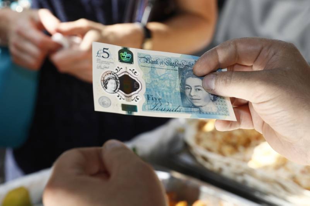 A food seller holds a new polymer five-pound note at Whitecross Street Market in London September 13, 2016. — Reuters pic