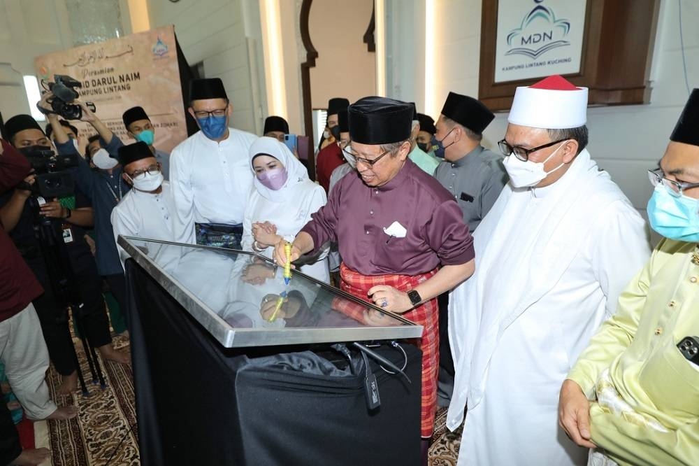 Abang Johari signing the plaque to mark the opening of Masjid Darul Naim. Also seen is Sharifah Hasidah (fourth right).  —  Borneo Post Online pic