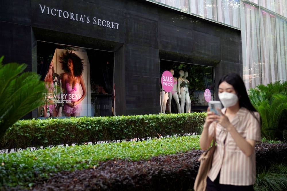 A woman, wearing a face mask following the coronavirus disease outbreak, walks past sale signs on a display window of a Victoria’s Secret store in Shanghai, China June 21, 2022. Picture taken June 21, 2022. — Reuters pic