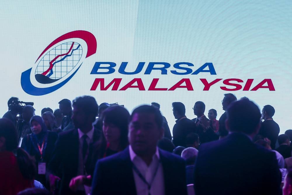 The silhouettes of attendees are seen in front of a Bursa Malaysia screen at the Invest Malaysia 2019 Conference at Shangri-La Hotel in Kuala Lumpur March 19, 2019. — Picture by Firdaus Latif