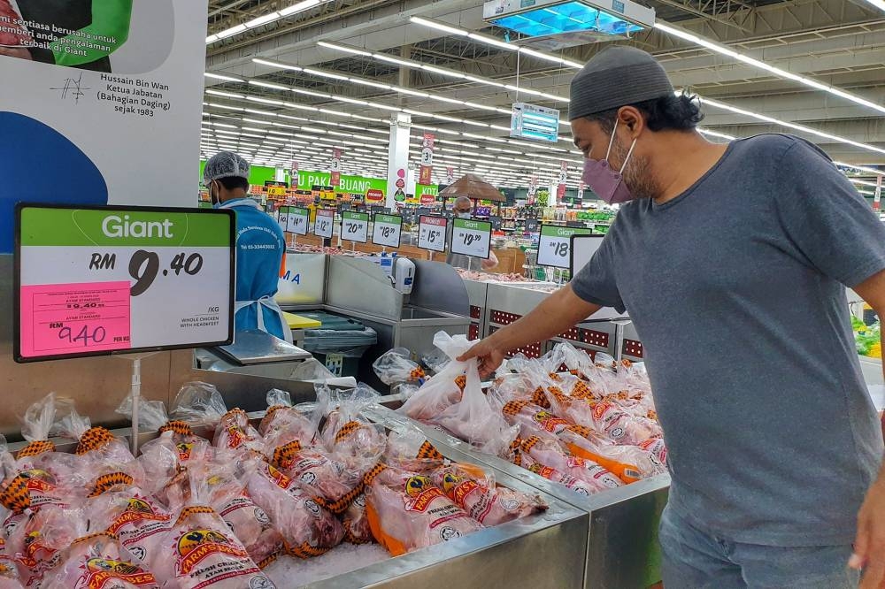 A man buys a whole chicken at a supermarket in Petaling Jaya, July 1, 2022. — Picture by Ahmad Zamzahuri