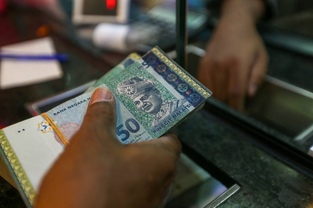 A man accepts Malaysian ringgit from a money changer May 24, 2022 — Picture by Devan Manuel