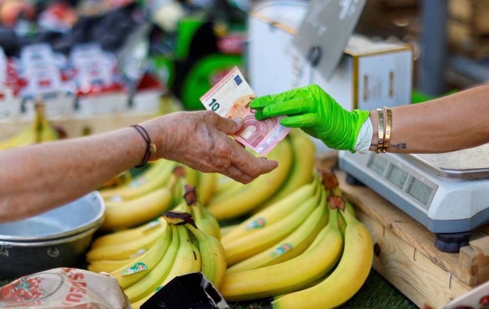 A shopper pays with a ten Euro bank note at a local market in Nice, France, June 7, 2022. — Reuters pic