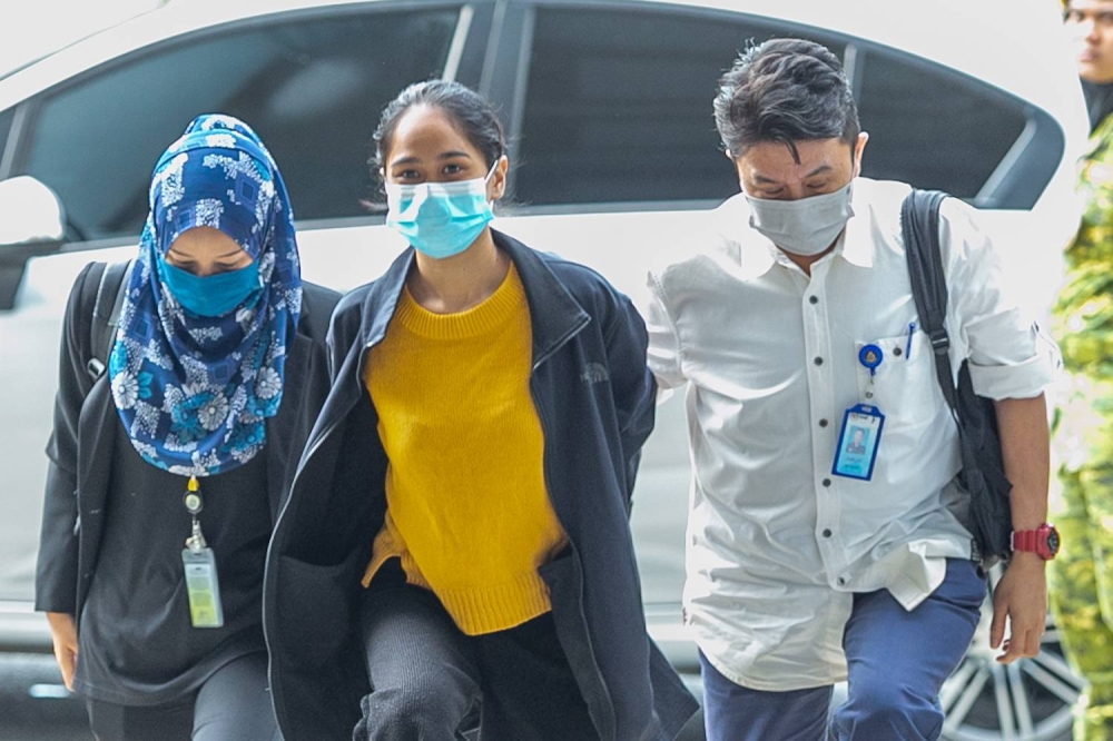 Siti Nuramira Abdullah (centre) is escorted by plainclothes police officers at the Kuala Lumpur High Court Complex on July 13, 2022. — Picture by Devan Manuel