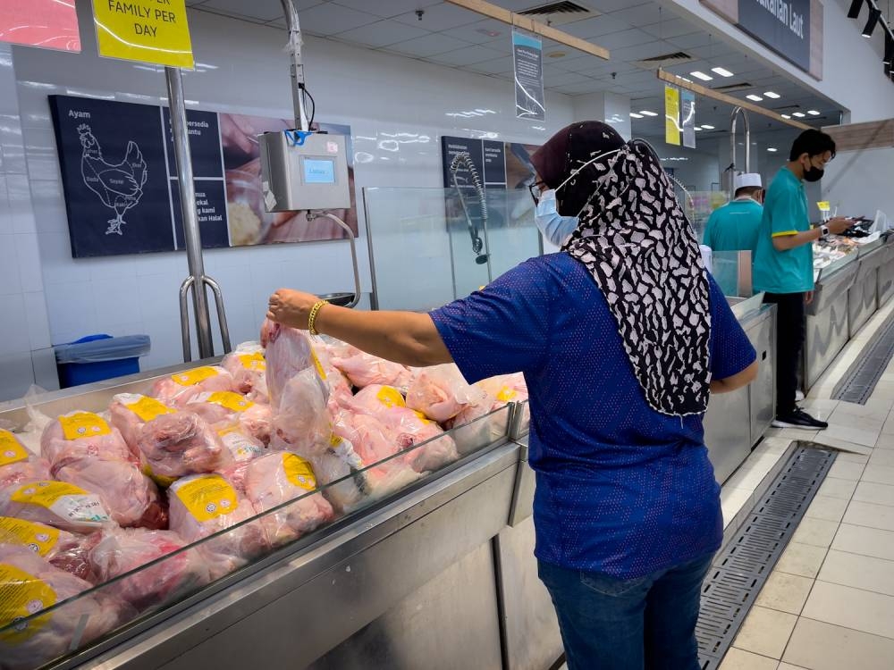 A woman picks out a bag of whole chicken at Lotus hypermarket in Semenyih. June 08,2022 — Picture by Devan Manuel