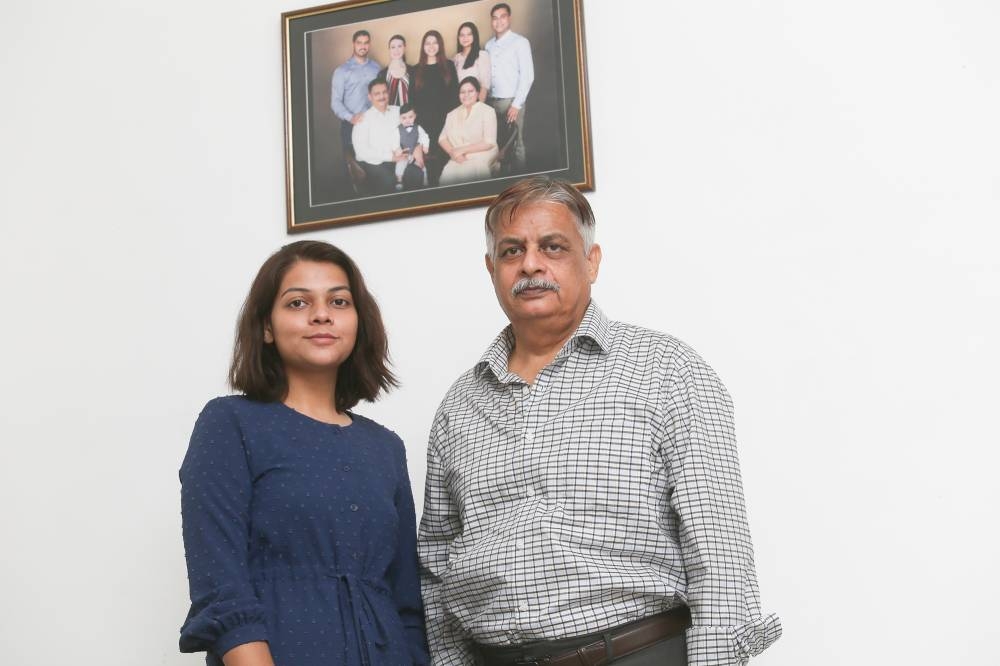 Niba Zaidi, the youngest of Malaysian Sabeena Syed Jafer Hussain Zaidi’s four children with her Pakistani father Syed Riaz Zaidi at their home in Taman Damai Utama, Puchong, July 11, 2022. A family portrait hangs on the wall behind them. — Picture by Choo Choy May