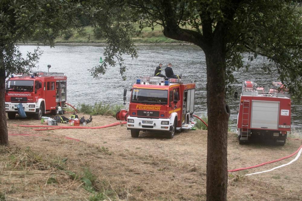 Firefighters rest as their engines refill with water while a wildfire continues to burn in a forest near the town of Schmilka, eastern Germany, on July 27, 2022, near the border with the Czech Republic. — AFP pic