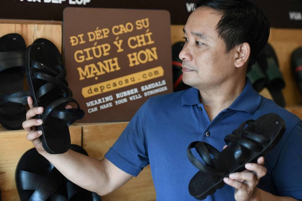 This photo taken on July 5, 2022 shows Nguyen Tien Cuong posing with his company's rubber sandals at a showroom in Hanoi. — AFP pic