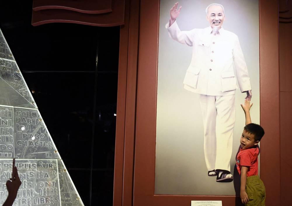 This photo taken on July 5, 2022 shows a boy posing in front of a photo of former president Ho Chi Minh wearing rubber sandals inside the Ho Chi Minh museum in Hanoi. — AFP pic