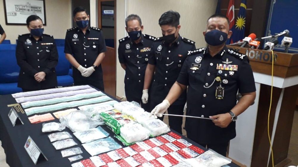 Johor police chief Datuk Kamarul Zaman Mamat (far right) with the seized drugs from the operation. — Picture by Ben Tan