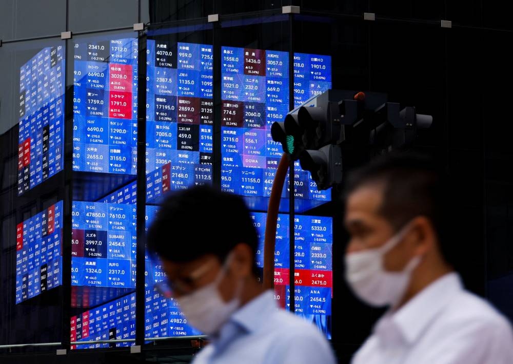 People pass by an electronic screen showing Japan's Nikkei share price index inside a conference hall  in Tokyo June 14, 2022. — Reuters pic