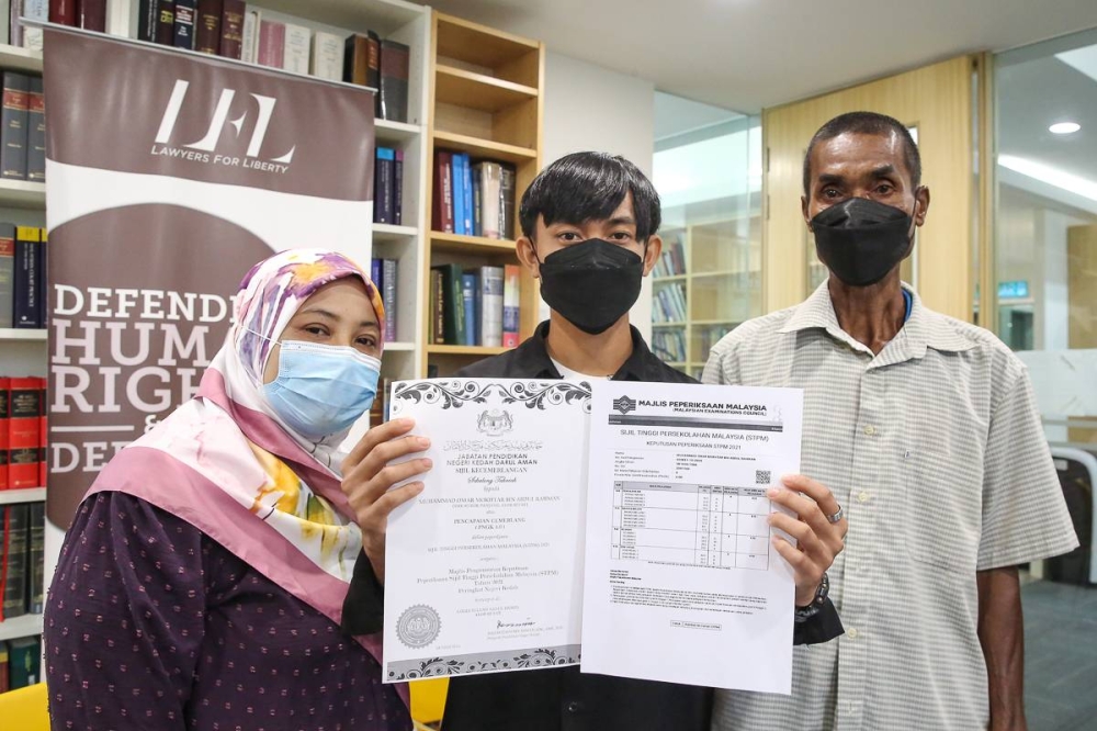 Muhammad Omar Mokhtar who is stateless (centre) poses for a pictures with his STPM results during a press conference at the Lawyer for Liberty office in Petaling Jaya August 29, 2022. — Picture by Yusof Mat Isa