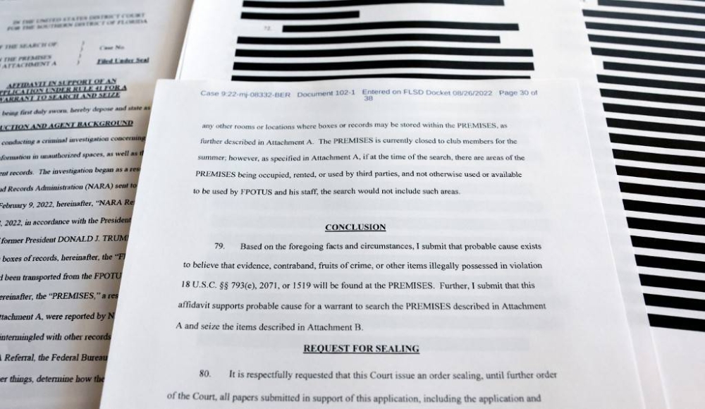 In this photo illustration, pages are viewed from the government’s released version of the FBI search warrant affidavit for former President Donald Trump's Mar-a-Lago estate on August 27, 2022 in California. The 32-page affidavit was heavily redacted for the protection of witnesses and law enforcement and to ensure the ‘integrity of the ongoing investigation’. — Getty Images via AFP