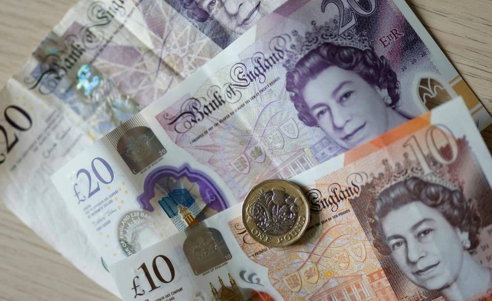 A file photo taken on April 22, 2022 shows sterling pounds coins and banknotes displayed on a table, in London. — AFP pic