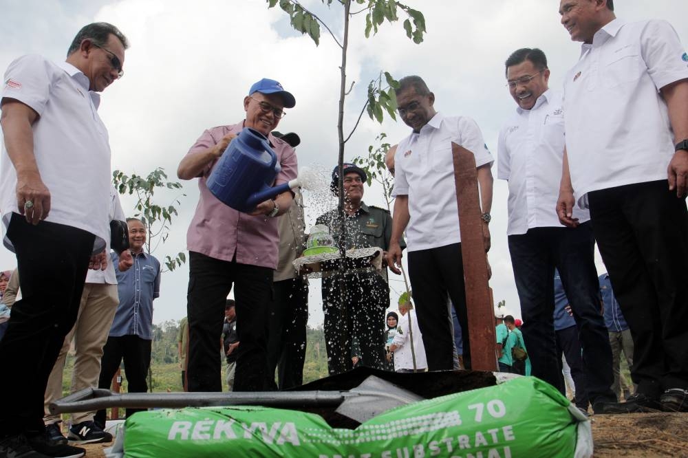 Minister of Energy and Natural Resources Datuk Seri Takiyuddin Hassan (third right) watched as Pahang Menteri Besar Datuk Seri Wan Rosdy Wan Ismail (fifth right) watered the Merawan Siput Jantan trees that were planted at Tasik Chini Biosphere Reserve in Pekan, September 10, 2022. — Bernama pic