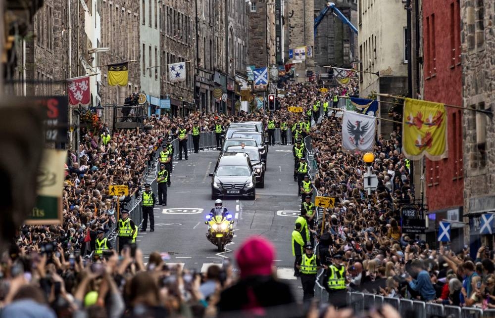 Members of the public gather along the Royal Mile to watch the hearse carrying the coffin of Queen Elizabeth II, as it is driven through Edinburgh towards the Palace of Holyroodhouse, on September 11, 2022. — AFP pic