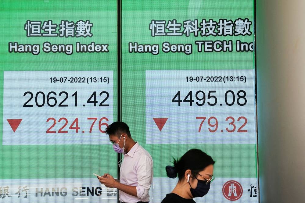 People walk past a screen displaying the Hang Seng stock index at Central district, in Hong Kong, China July 19, 2022. — Reuters pic