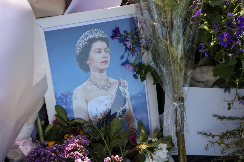 An image of Britain's Queen Elizabeth is surrounded by flowers at a makeshift memorial following her death, at the gates of Government House in Sydney, Australia, September 12, 2022. — Reuters pic