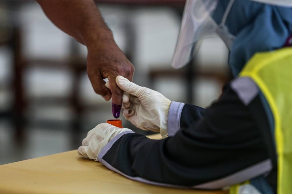 Voters cast their ballot at the SMK Sri Muar polling station in Muar, Johor March 12, 2022. — Picture by Hari Anggara