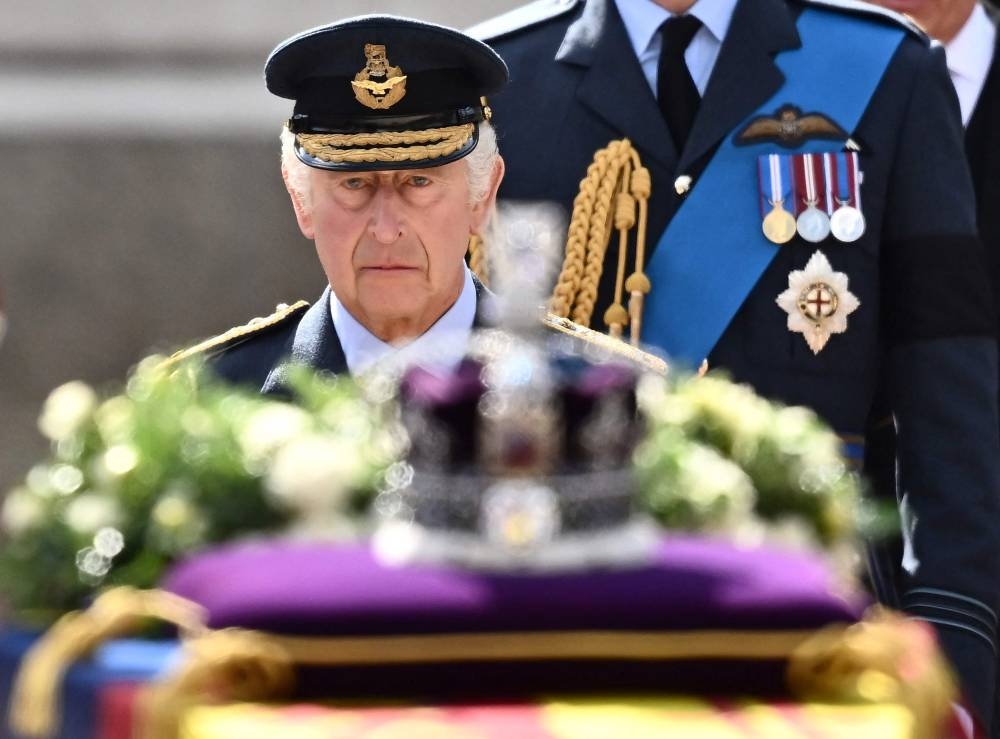 Britain’s King Charles III walks behind the coffin of Queen Elizabeth II, adorned with a Royal Standard and the Imperial State Crown and pulled by a Gun Carriage of The King’s Troop Royal Horse Artillery, during a procession from Buckingham Palace to the Palace of Westminster, in London September 14, 2022. — AFP pic