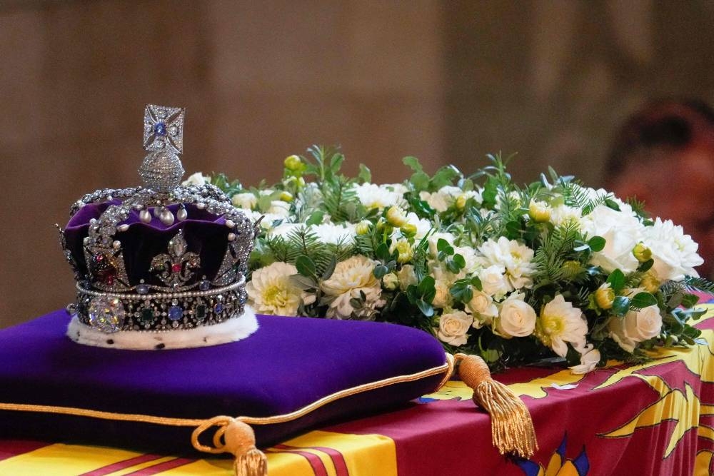 The coffin of Queen Elizabeth II, adorned with a Royal Standard and the Imperial State Crown, arrives at the Palace of Westminster, following a procession from Buckingham Palace, in London on September 14, 2022. — Gregorio Borgia/Pool/AFP pic