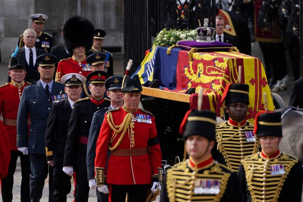 The coffin of Queen Elizabeth II, draped in the Royal Standard with the Imperial State Crown placed on top, is carried on a horse-drawn gun carriage during the ceremonial procession from Buckingham Palace to Westminster Hall, London September 14, 2022. — Reuters pic