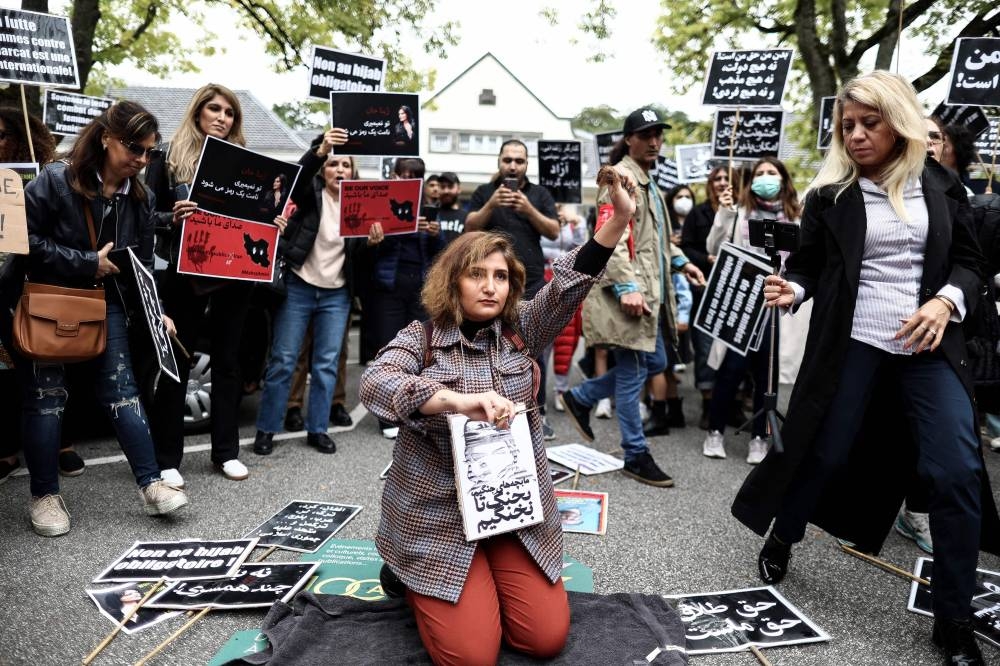 A woman cuts her hair during a demonstration in support of Mahsa Amini in front of the Iranian embassy in Brussels, on September 23, 2022, following the death of an Iranian woman after her arrest by the country's morality police in Tehran.― AFP pic