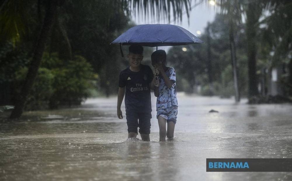 File picture of children walking in the rain while holding an umbrella during flash floods. — Picture via Twitter/Bernama