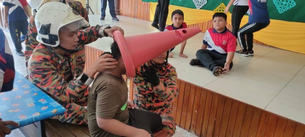 Firemen from the Pontian fire station attempting to remove the cone from the 10-year-old victim’s head at SK Api Api in Pontian, September 27, 2022. — Picture courtesy of the Johor Fire and Rescue Department