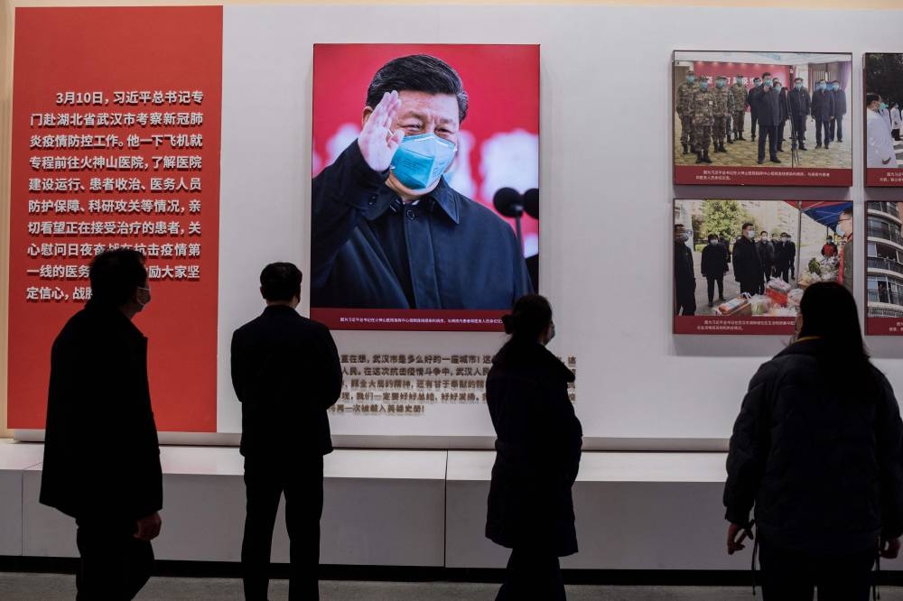 In this file photo taken on January 15, 2021, people walk past an image of China's President Xi Jinping during an exhibition about China's fight against the Covid-19 coronavirus at a convention centre that was previously a makeshift hospital for coronavirus patients in Wuhan. — AFP pic