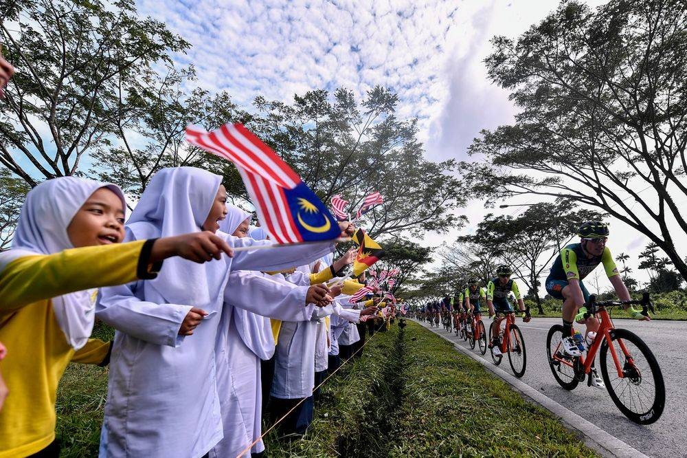 Schoolchildren waving flags as the Le Tour de Langkawi 2020 (LTdL) racing team competing in the first LTdL Tour series crosses Kuching Isthmus, February 7, 2020. — Bernama pic