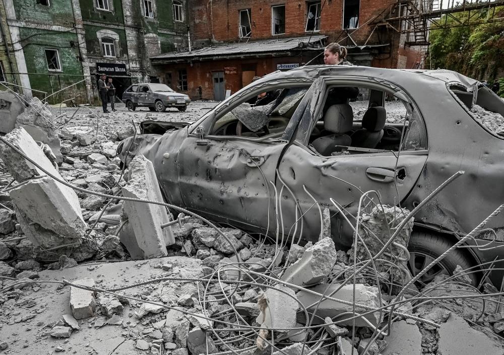 A woman stands near her destroyed car near an old mill, built around 1885, destroyed during a Russian missile attack in Zaporizhzhia, Ukraine October 14, 2022. ― Reuters pic