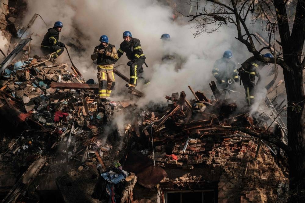 Ukrainian firefighters works on a destroyed building after a drone attack in Kyiv October 17, 2022. — AFP pic