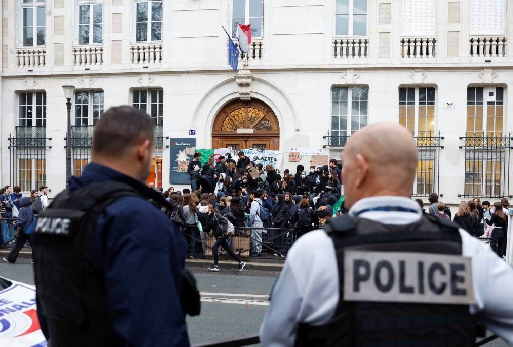 French police stand guard as students block the entrance of the Lycee Montaigne high school to protest as part of a nationwide day of strike in Paris October 18, 2022. — Reuters pic