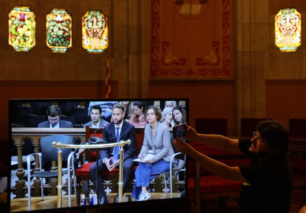 A journalist takes a photograph as Brazil’s Neymar is seen on a television screen while testifying as he stands trial on fraud and corruption charges over the transfer to FC Barcelona from Santos in 2013, Barcelona, Spain, October 18, 2022. — Reuters pic 